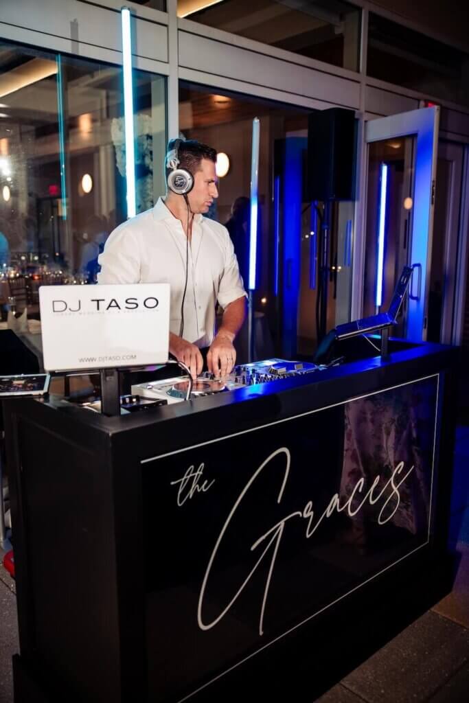 Boutique wedding DJ performing live at a luxury reception with custom DJ booth and lighting setup